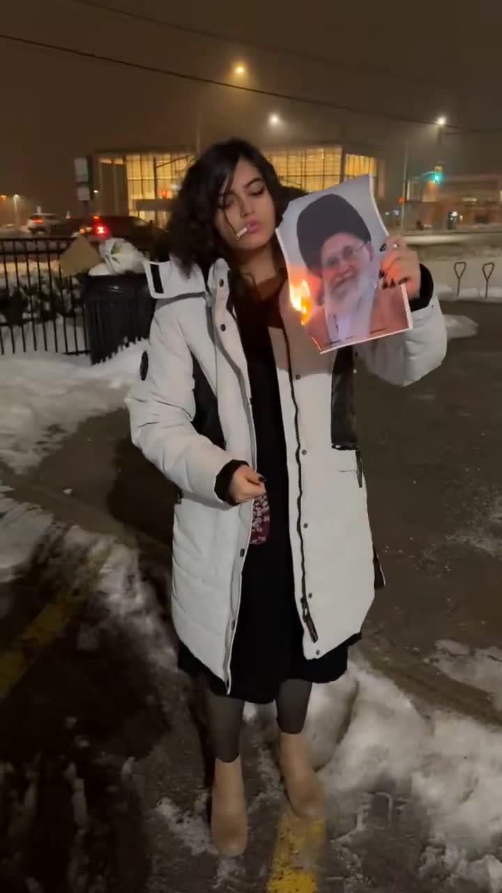 Xameneyinin yanan fotosu ile siqaret alışdıran qız